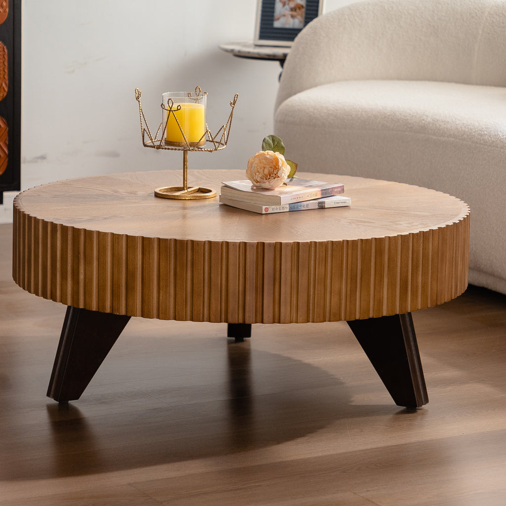 Round wooden coffee table with decorative items in a living room setting