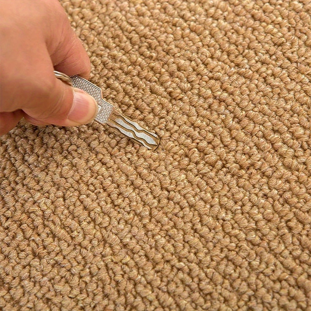 Hand holding a key with a keychain on a beige carpet