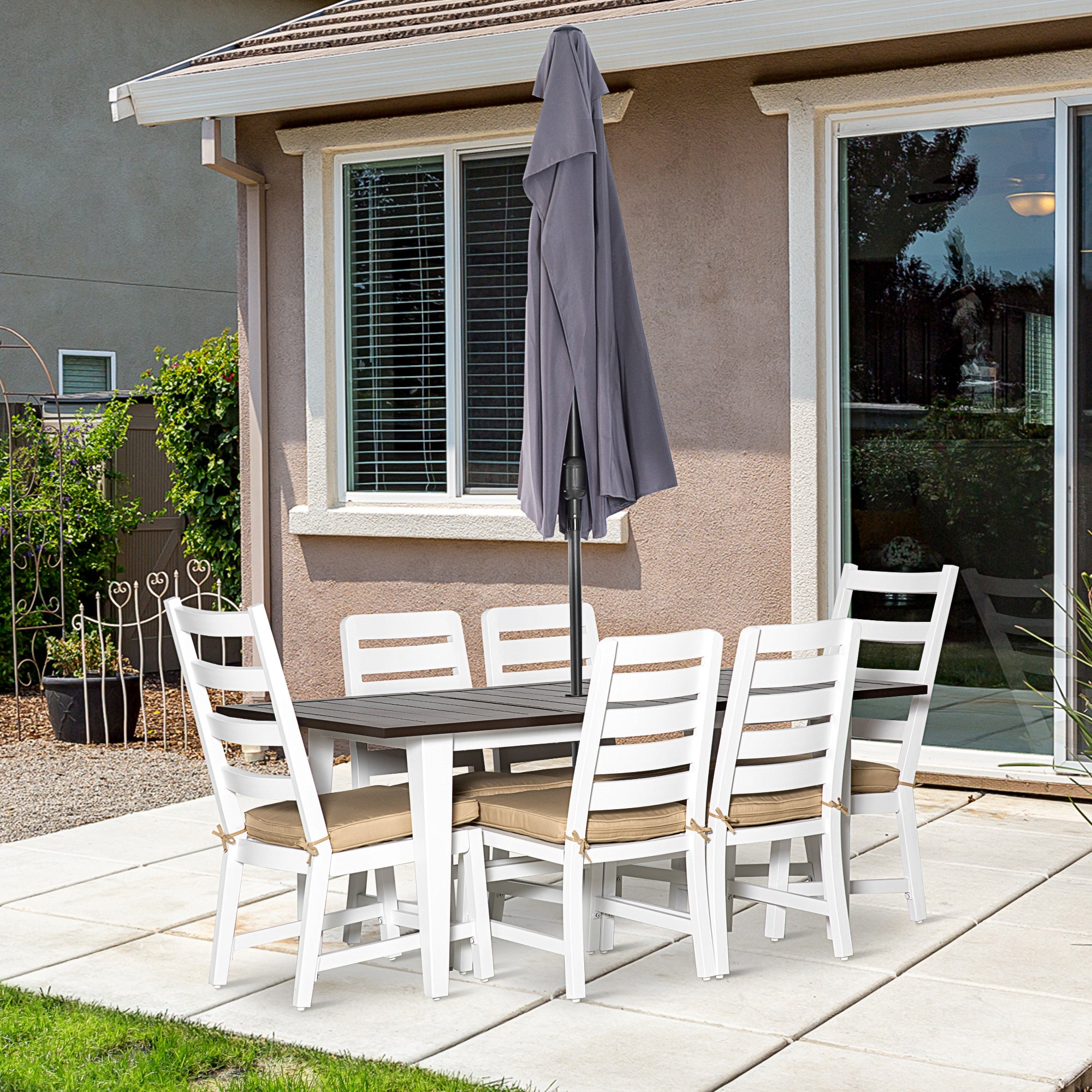 Outdoor patio set with table and chairs on a patio area in front of a house.