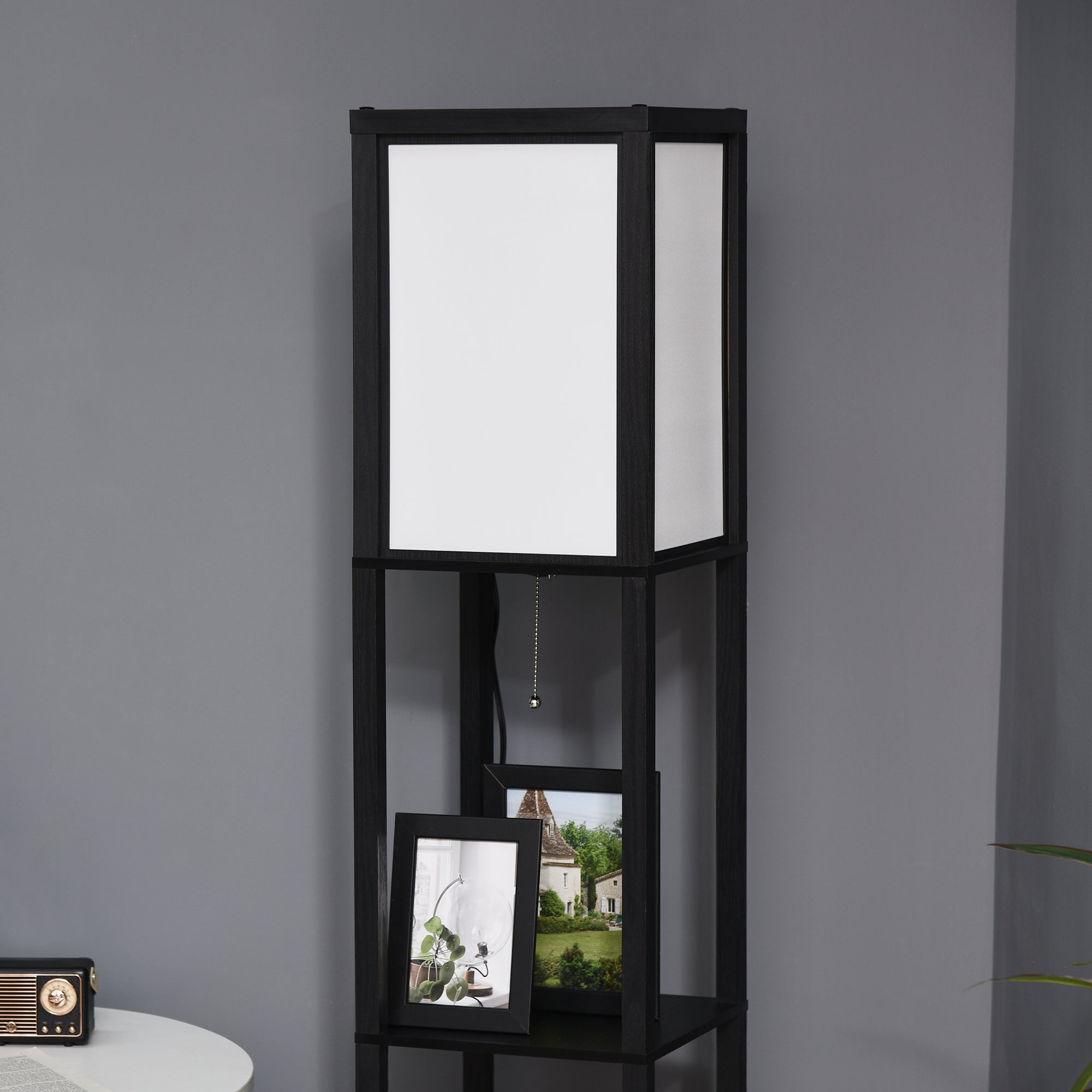 Black shelving unit with a white lampshade against a gray wall