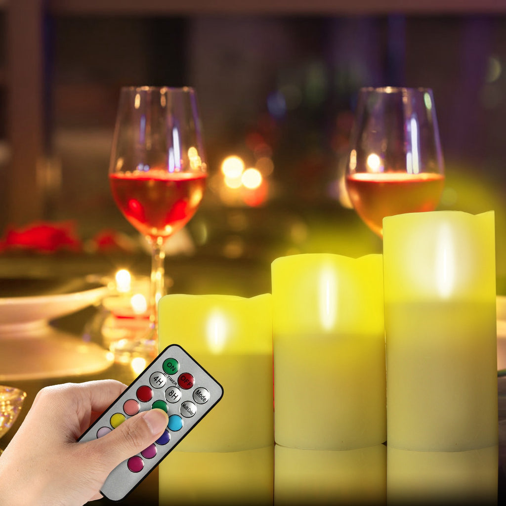 Hand holding a remote control over LED candles with wine glasses in the background