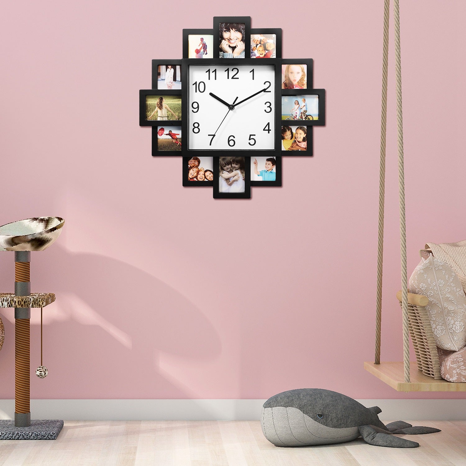 Wall clock with photo frames on a pink wall, surrounded by children's toys.