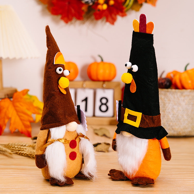 Two decorative gnomes dressed as turkeys on a wooden surface with pumpkins and leaves in the background.