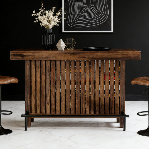 Walnut slatted wood bar table with metal footrest rail and lower storage shelf styled in a modern living room