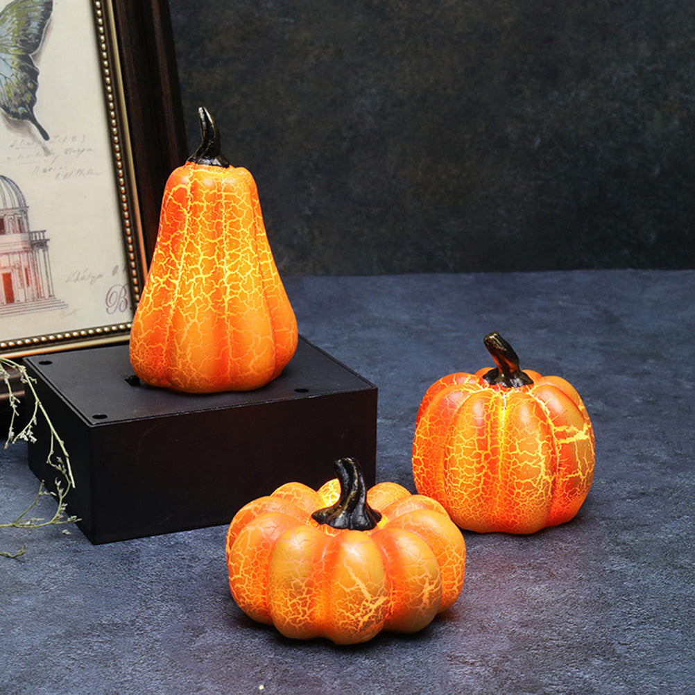 Three decorative pumpkins with a cracked texture on a dark surface, with a framed picture in the background.