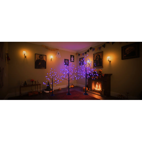 Living room with Halloween decorations, including lit trees and a fireplace.