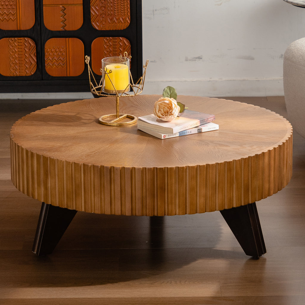 Round wooden coffee table with decorative items in a room setting
