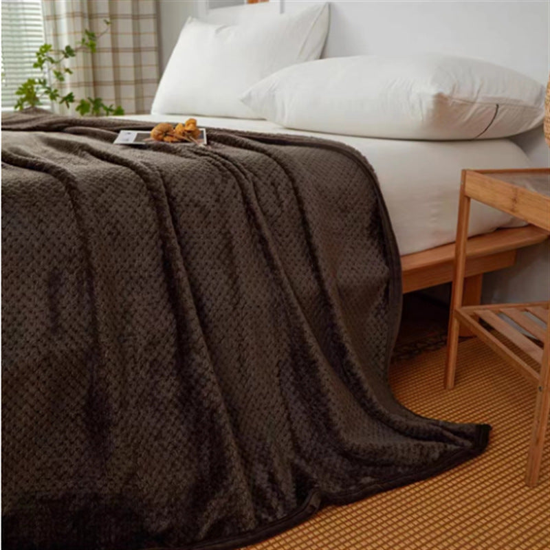 Brown blanket on a bed with white pillows and a wooden chair in a bedroom setting.