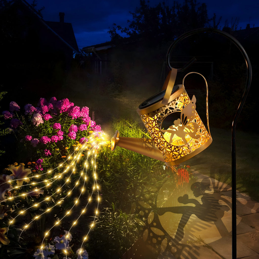 Decorative garden light with fairy design casting a warm glow on flowers and ground.