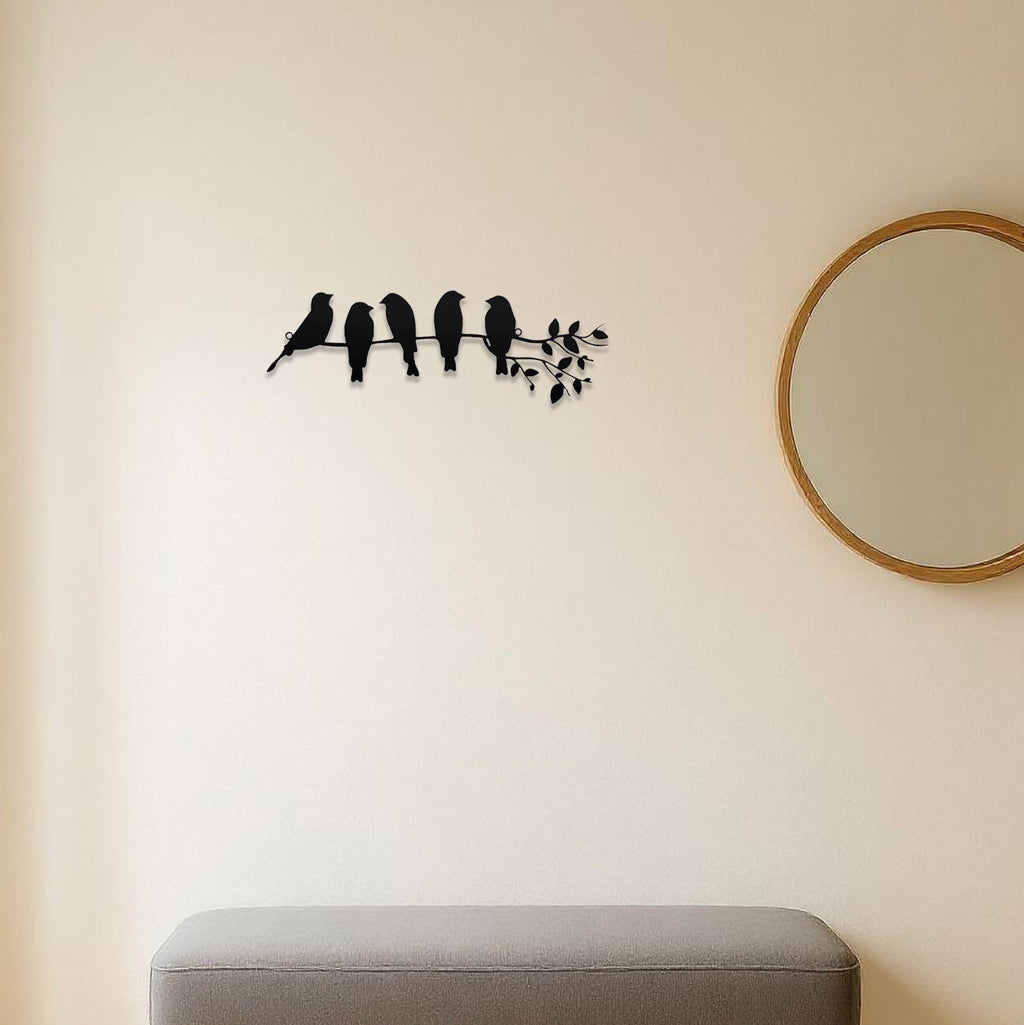 Decorative wall sticker of birds on a branch above a bench in a room.