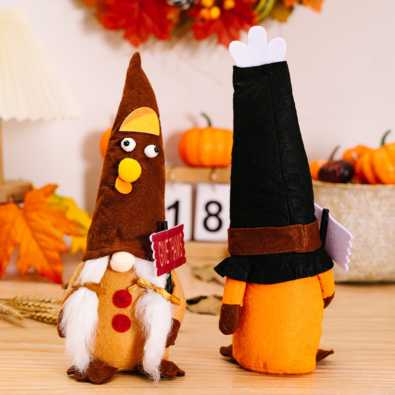 Two decorative figures resembling a turkey and a pilgrim on a wooden surface with pumpkins and leaves in the background.