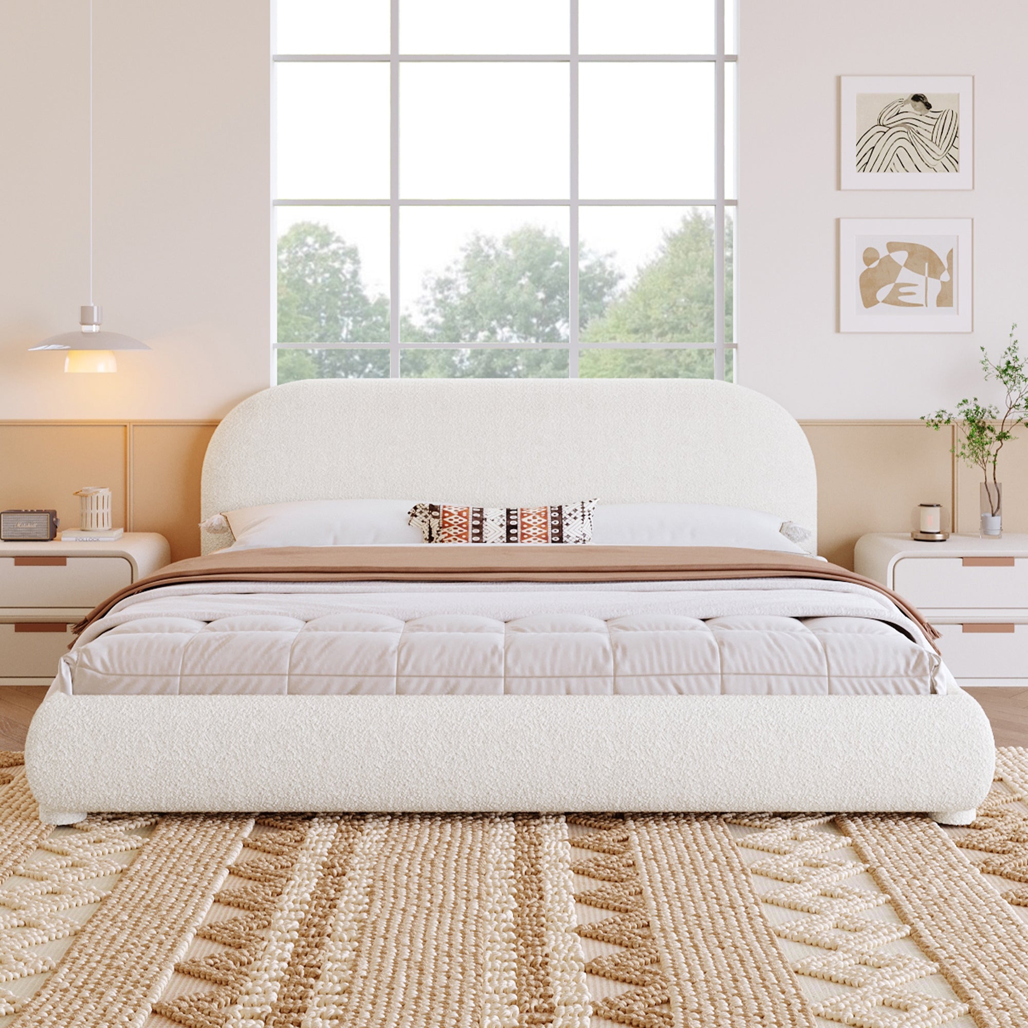 White upholstered bed in a bright bedroom with large windows.