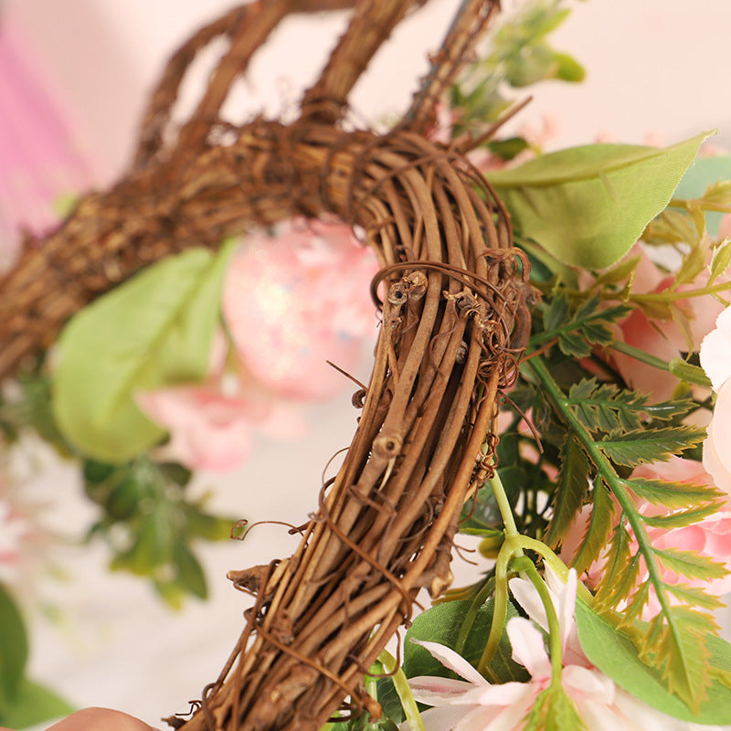 Decorative wreath with greenery and pink flowers on a blurred background