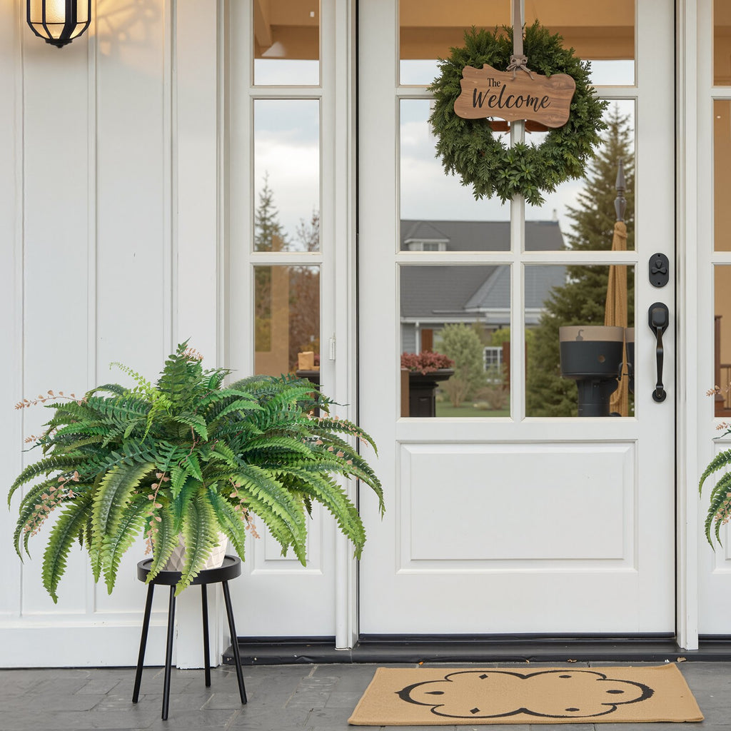 Front door with a wreath, potted fern, and welcome mat on a porch.