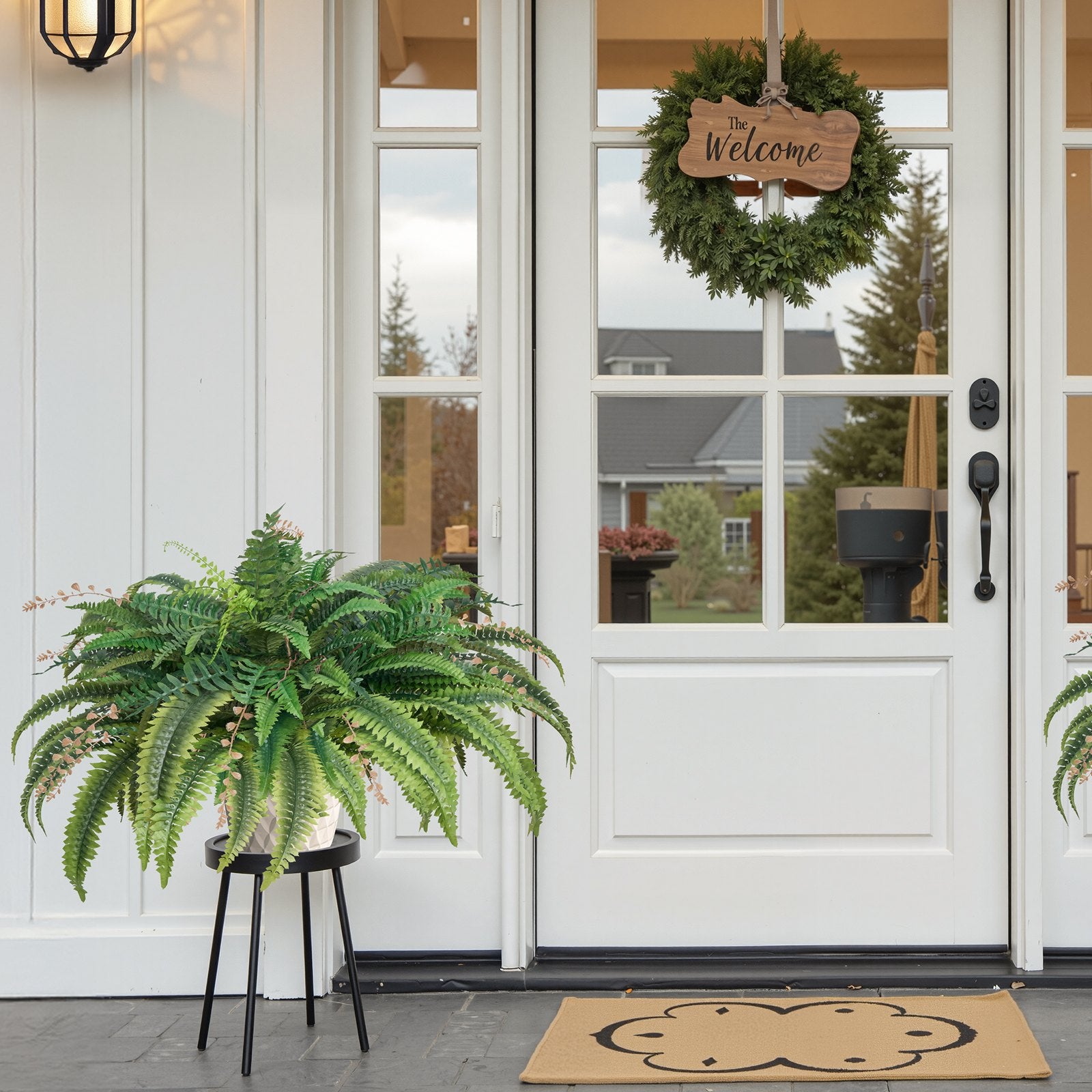 Front door with a wreath, potted fern, and welcome mat on a porch.