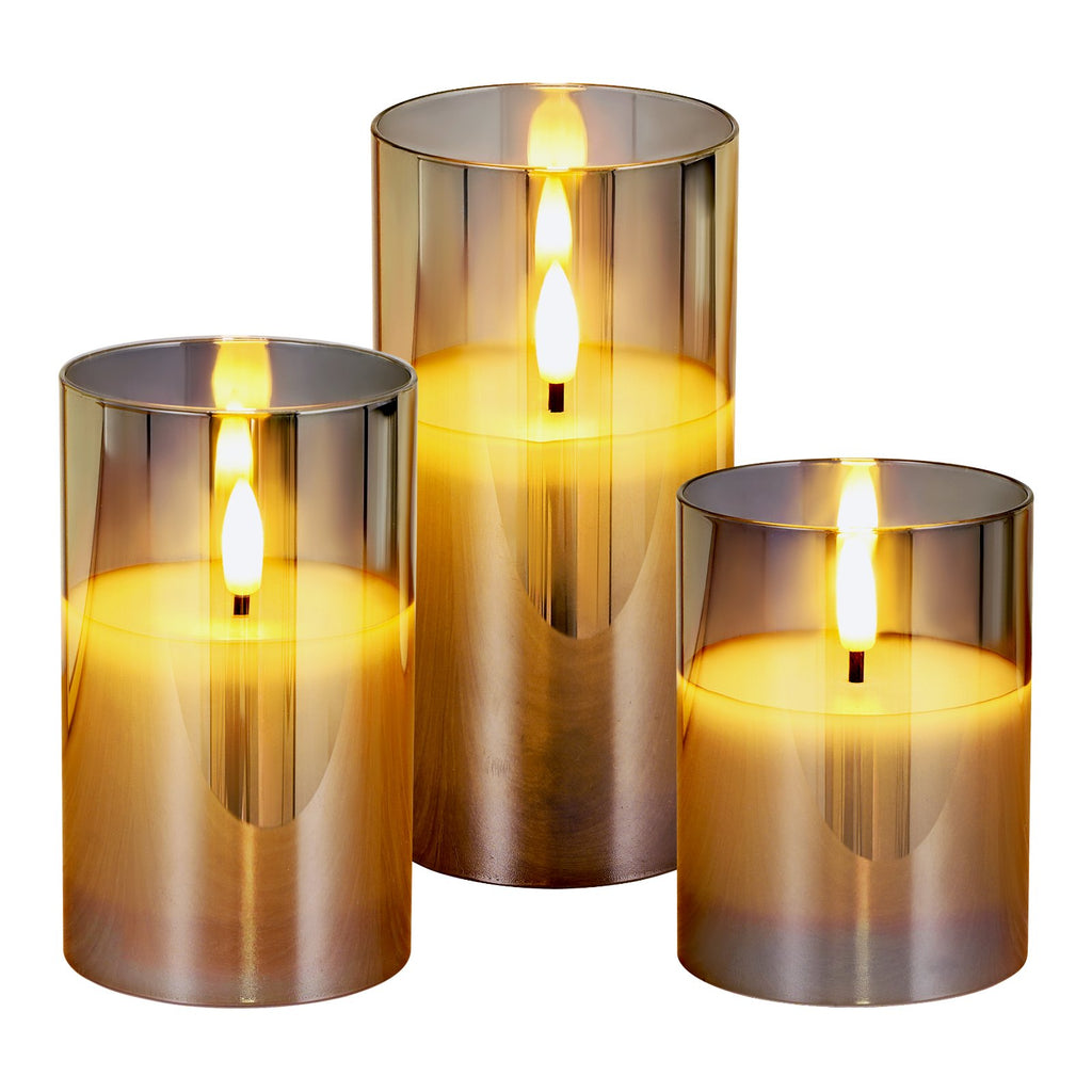 Three metallic candle holders with lit candles on a white background