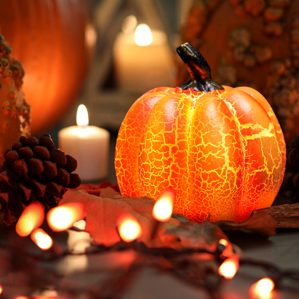 Decorative pumpkin with cracked texture, surrounded by candles and pinecones on a dark background