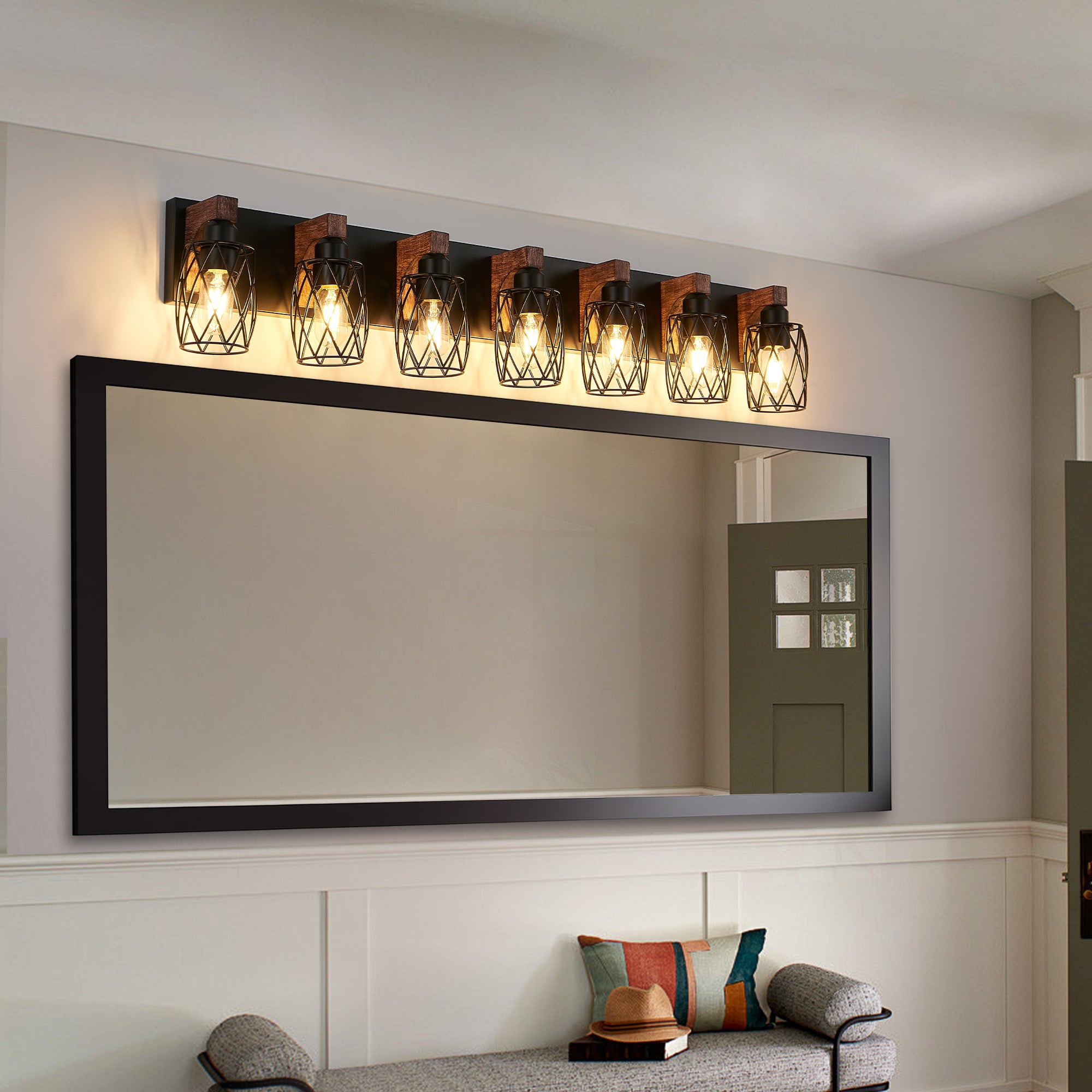 Wall-mounted light fixture with a large mirror above a bench in a room.