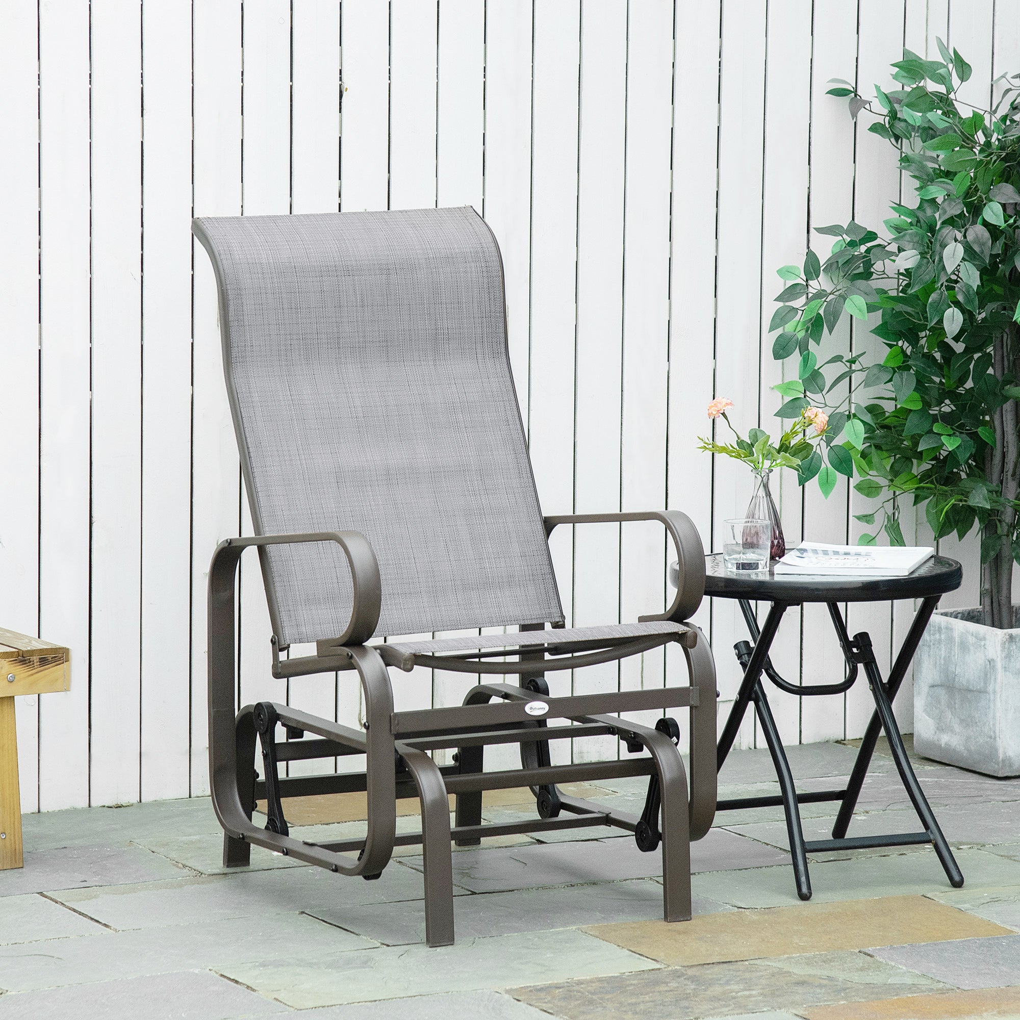 Gray outdoor recliner chair on a patio with a small table and plants.