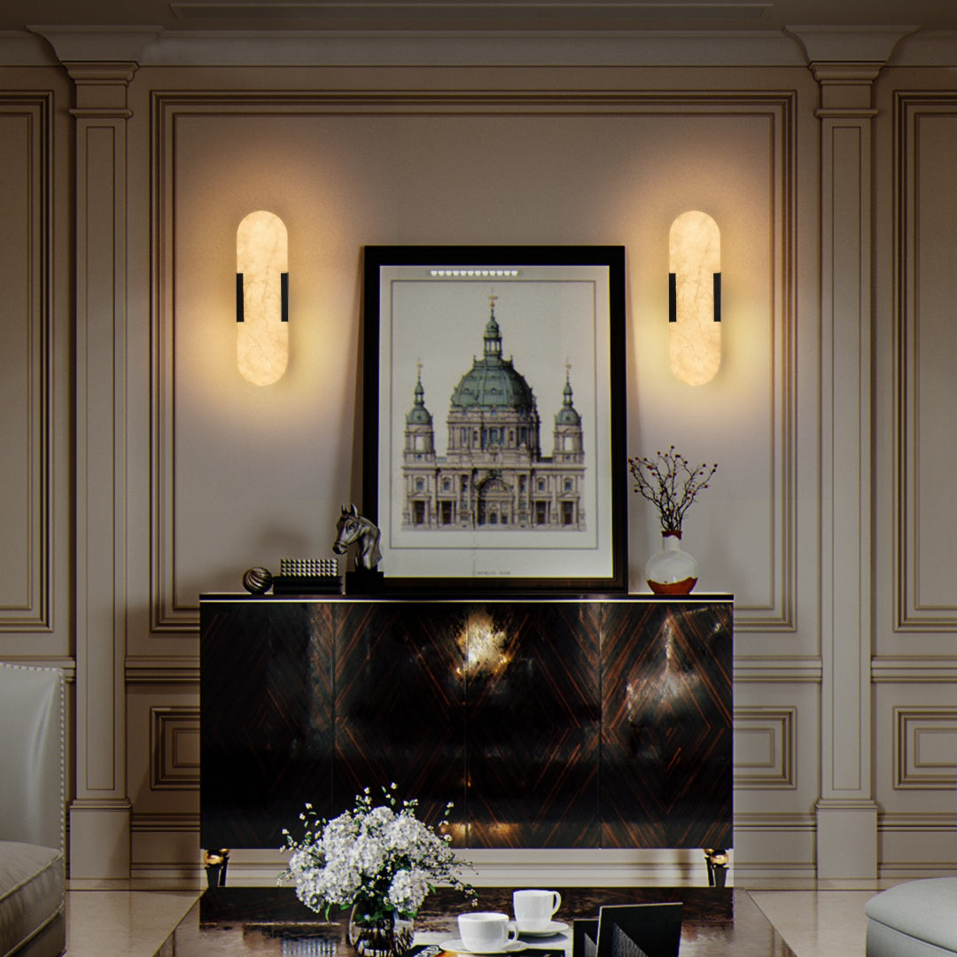 Decorative wall with framed artwork, sconces, and a console table.